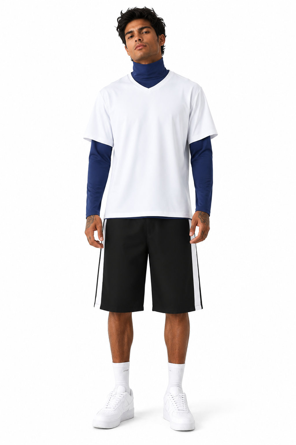 A male model stands against a white studio background wearing a white short-sleeve V-neck t-shirt layered over a navy blue long-sleeve top, paired with black athletic shorts featuring white side stripes, white socks, and white sneakers.