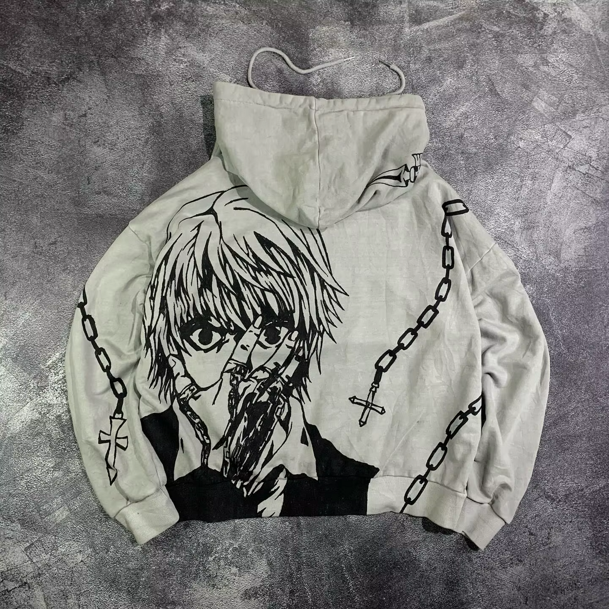 Flat lay of the back of a light grey streetwear hoodie featuring a massive Kurapika manga portrait and chain graphics by Skaiiy.
